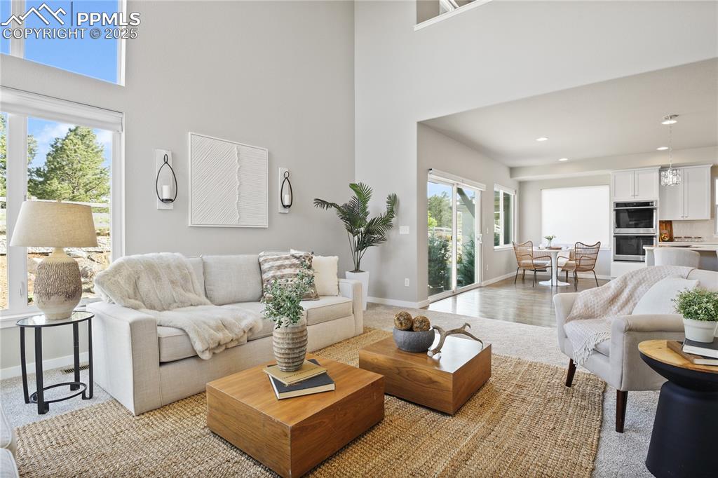 Image 15 of 50: Living area featuring a high ceiling, baseboards, and recessed lighting