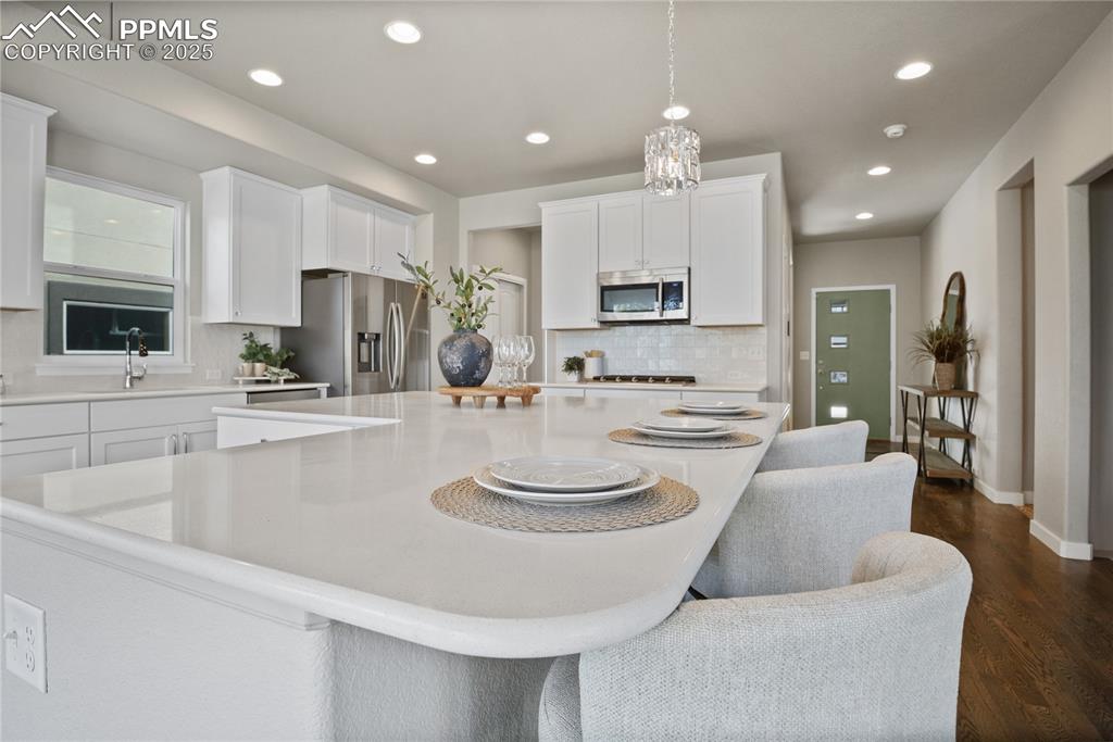 Image 18 of 50: Kitchen with stainless steel appliances, a center island, decorative backsp