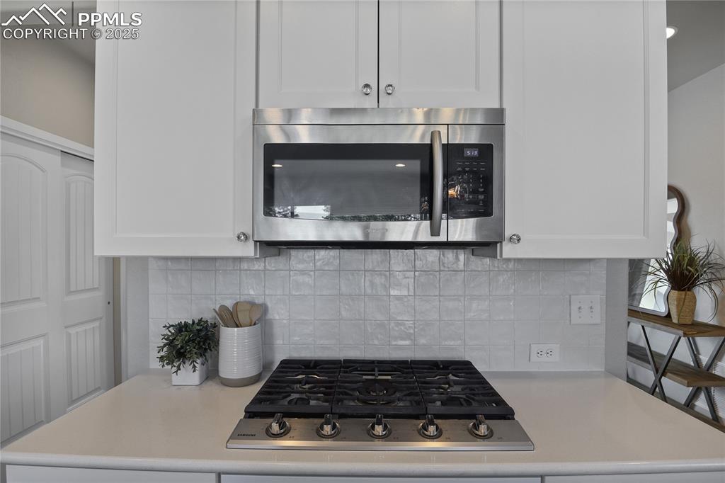 Image 19 of 50: Kitchen with appliances with stainless steel finishes, light countertops, a
