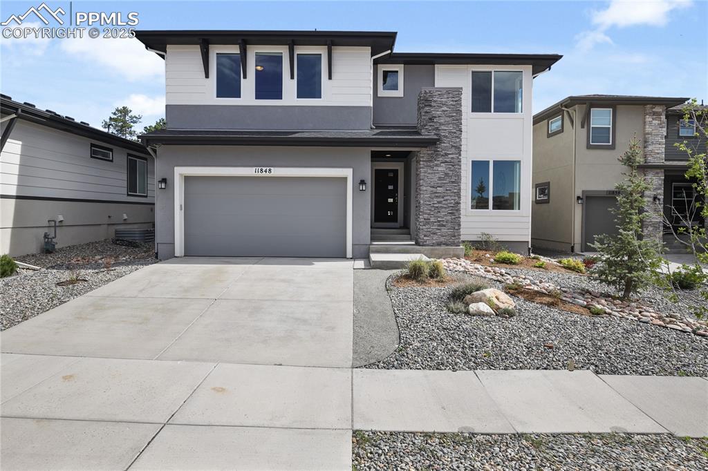 Image 2 of 50: View of front facade with stucco siding, concrete driveway, and an attached
