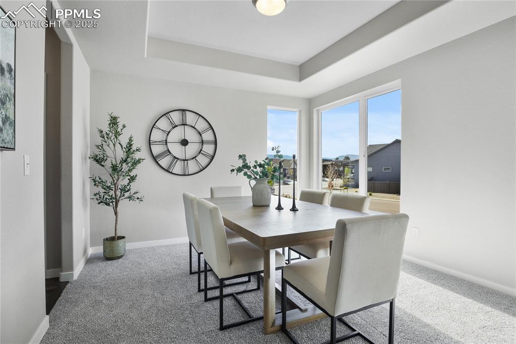 Image 20 of 50: Dining area with carpet floors, baseboards, and a tray ceiling