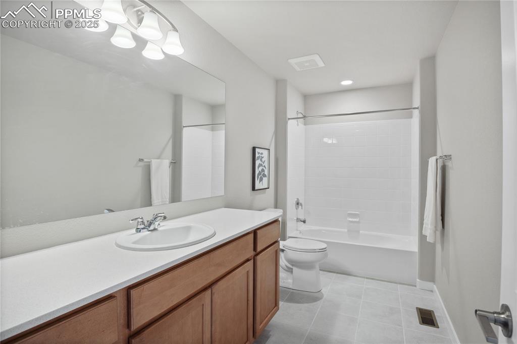 Image 23 of 50: Bathroom with tile patterned floors, toilet, vanity, and shower / tub combi