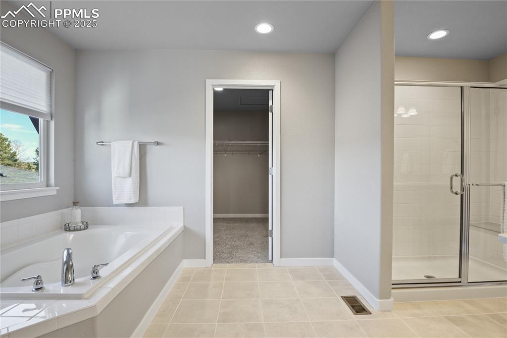 Image 31 of 50: Bathroom with a stall shower, a garden tub, a walk in closet, tile patterne