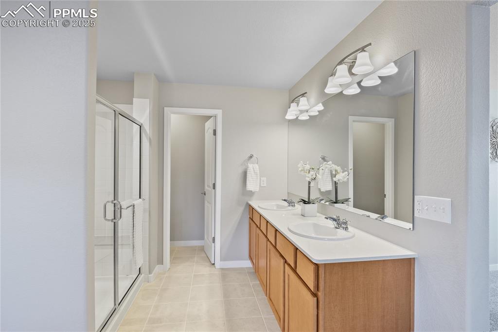 Image 32 of 50: Bathroom with a stall shower, tile patterned floors, double vanity, and bas