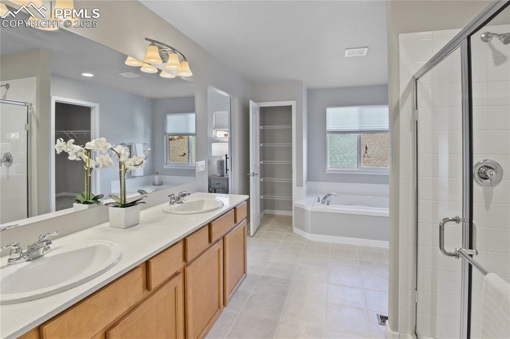 Image 34 of 50: Full bathroom featuring a shower stall, a spacious closet, a bath, tile pat