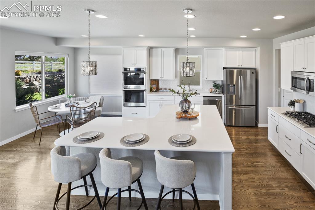 Image 37 of 50: Kitchen featuring stainless steel appliances, a breakfast bar area, light c
