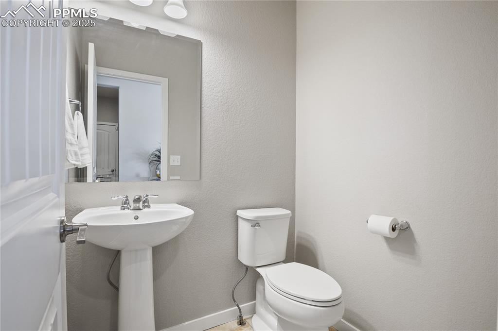 Image 38 of 50: Bathroom featuring toilet, a sink, and baseboards