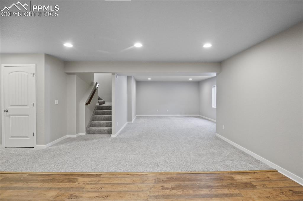Image 39 of 50: Basement with baseboards, stairway, recessed lighting, carpet flooring, and