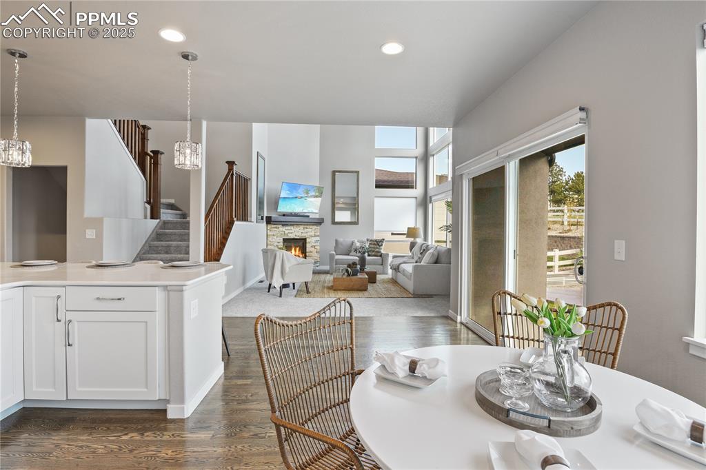 Image 9 of 50: Dining space with a chandelier, dark wood-style floors, a stone fireplace,