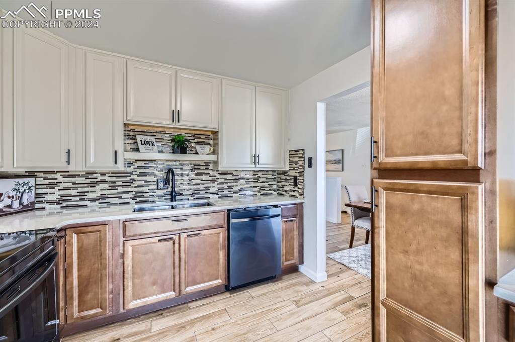 Image 3 of 28: Kitchen featuring black range oven, sink, stainless steel dishwasher, decor