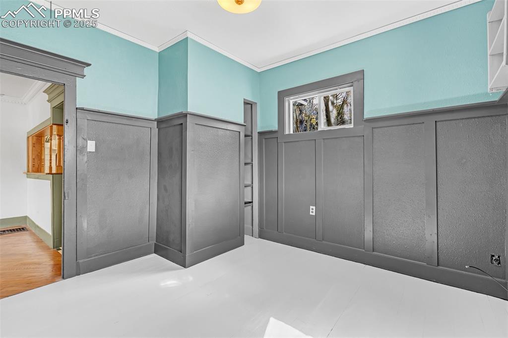 Image 26 of 50: Unfurnished bedroom with ornamental molding, a wainscoted wall, and a decor