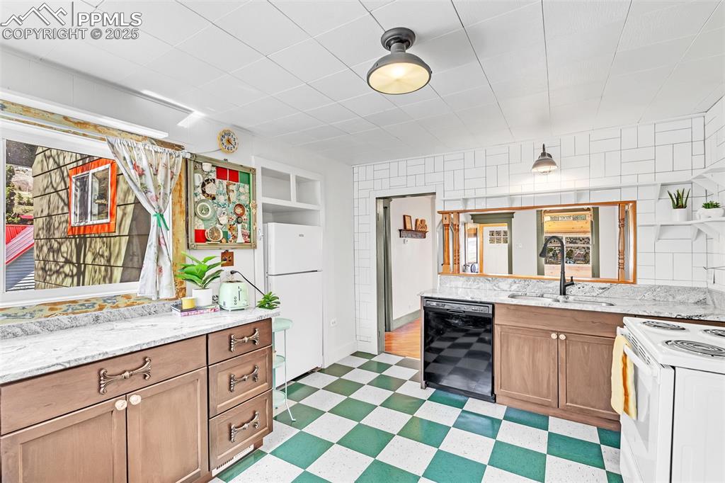 Image 29 of 50: Kitchen featuring white appliances, a sink, light flooring, and light stone