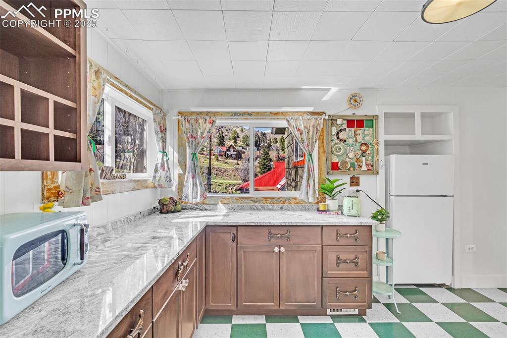 Image 30 of 50: Kitchen featuring white appliances, light floors, light stone countertops,
