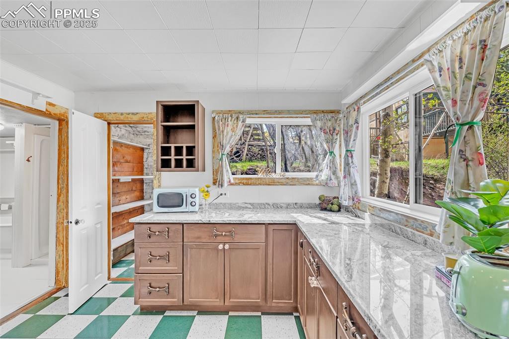 Image 31 of 50: Kitchen featuring white microwave, light flooring, light stone countertops,