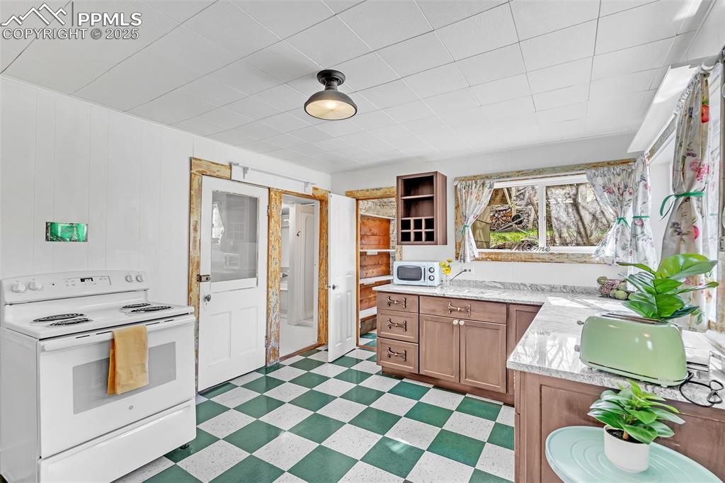 Image 32 of 50: Kitchen featuring white appliances, light flooring, open shelves, brown cab