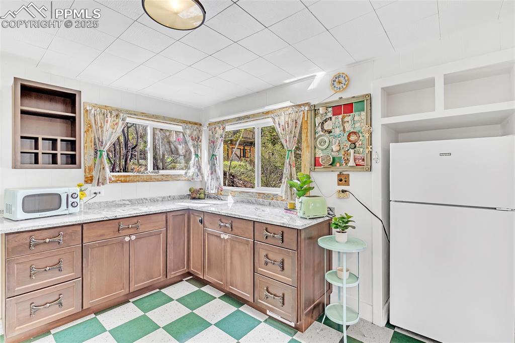 Image 33 of 50: Kitchen featuring open shelves, light floors, brown cabinetry, and light st