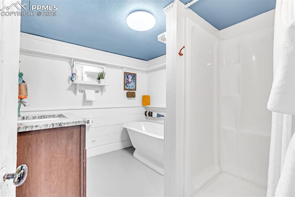 Image 37 of 50: Full bathroom featuring a sink, a shower, a textured ceiling, and a soaking