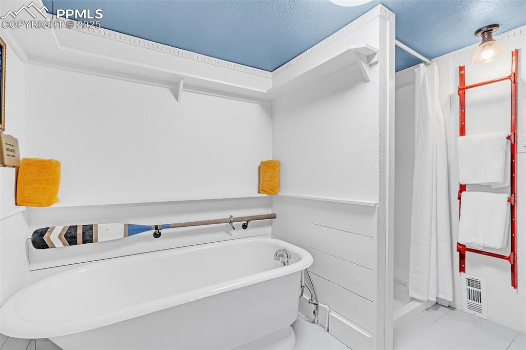 Image 38 of 50: Bathroom featuring a stall shower, a freestanding bath, and tile patterned