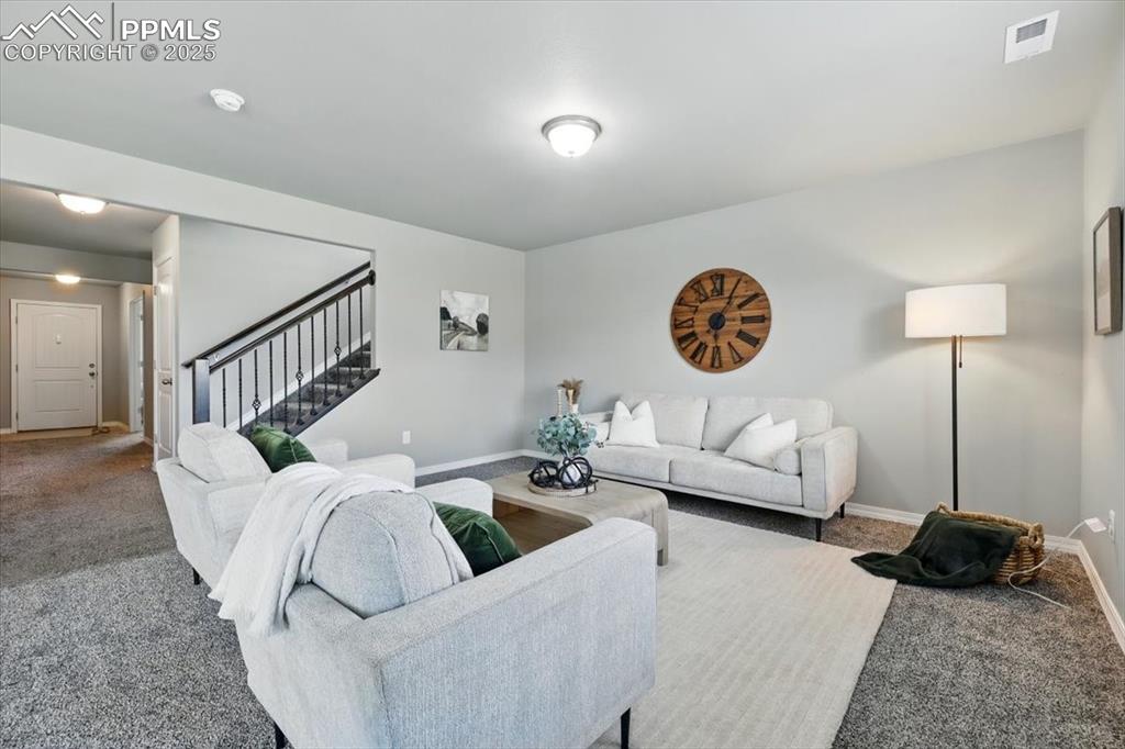 Image 11 of 45: Living area with stairway and carpet flooring