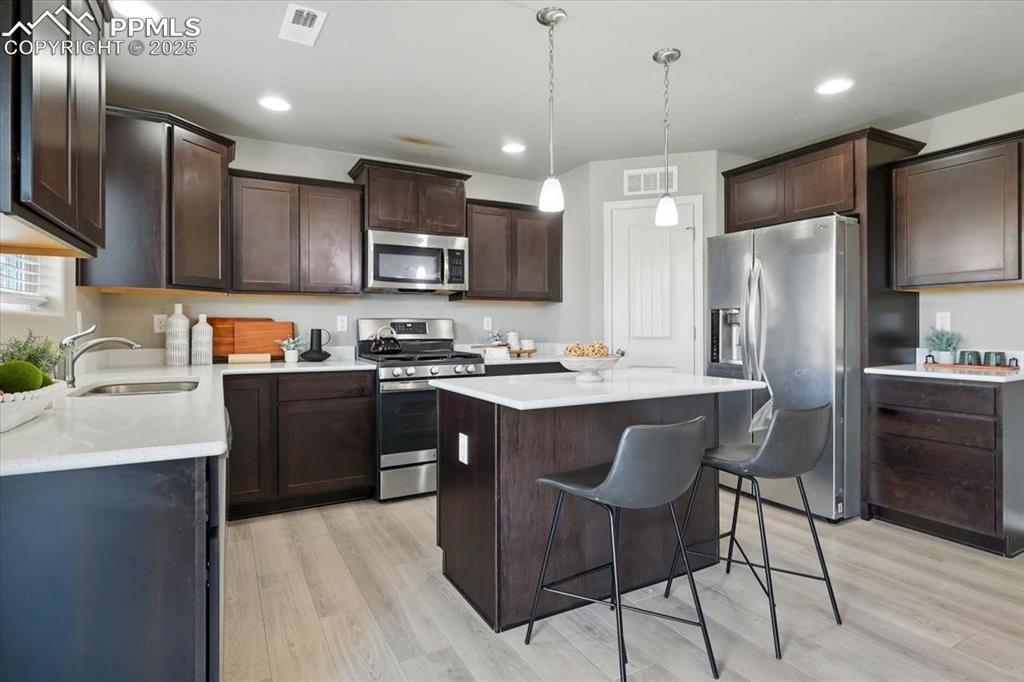 Image 18 of 45: Kitchen featuring appliances with stainless steel finishes, dark brown cabi