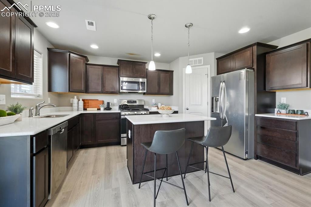 Image 19 of 45: Kitchen with appliances with stainless steel finishes, a center island, lig