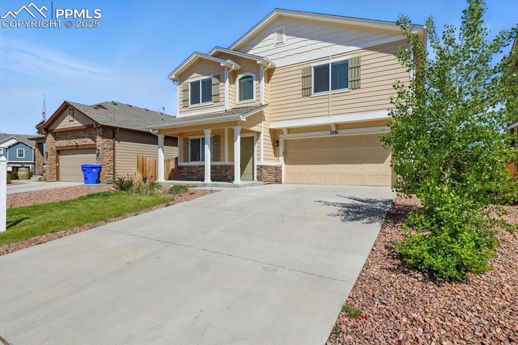 Image 2 of 45: View of front of home featuring a porch, stone siding, a garage, and concre