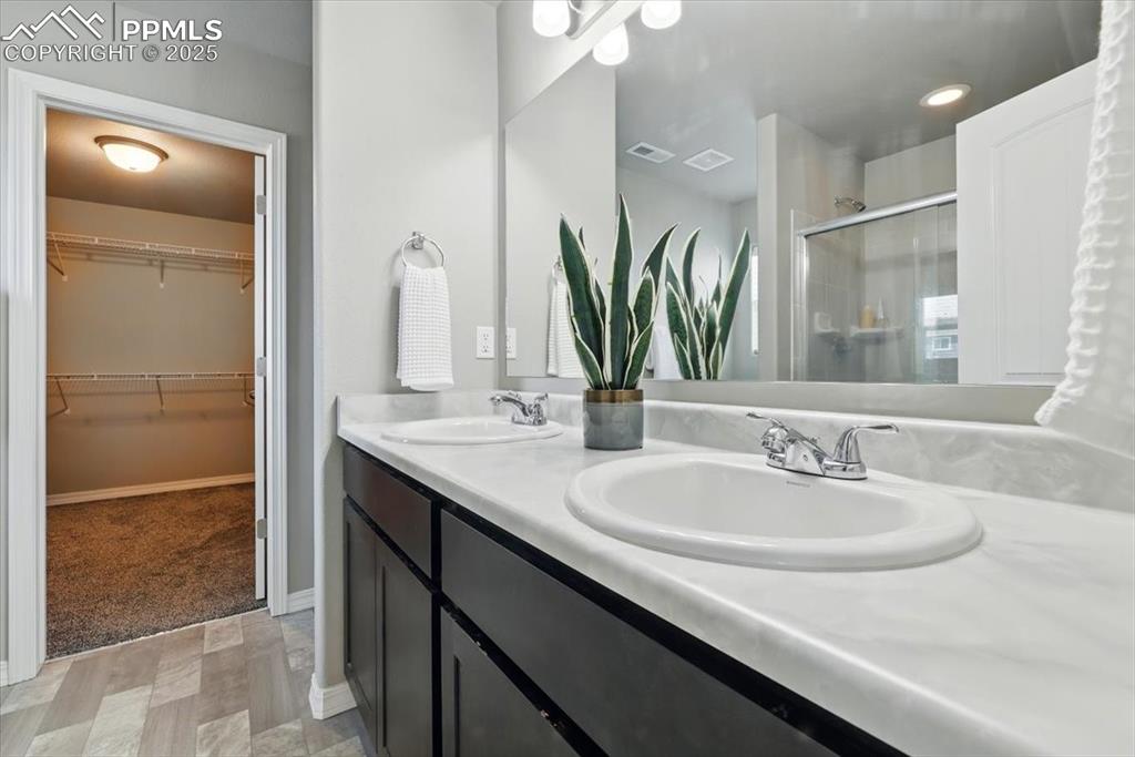 Image 27 of 45: Bathroom with a stall shower, double vanity, and a walk in closet