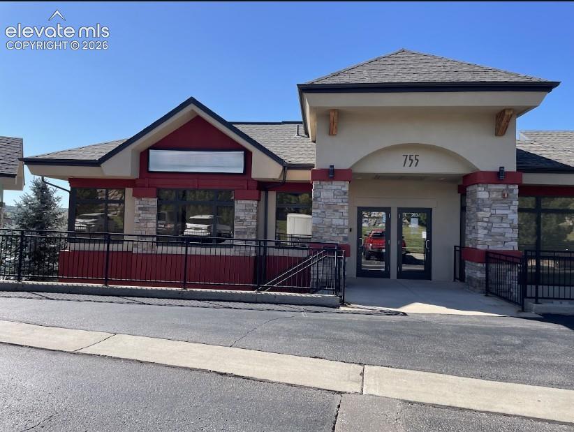 Caption: Stucco and stone exterior with prominent arched entryway and dual glass doors
