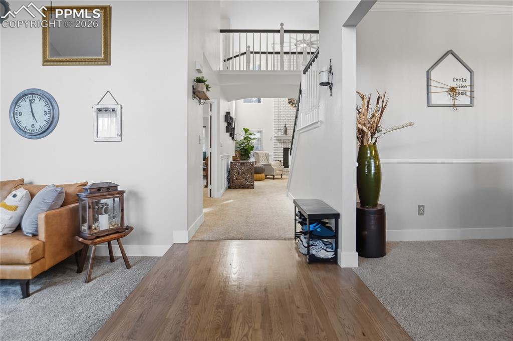 Image 14 of 45: Hall featuring carpet, a high ceiling, and wood finished floors