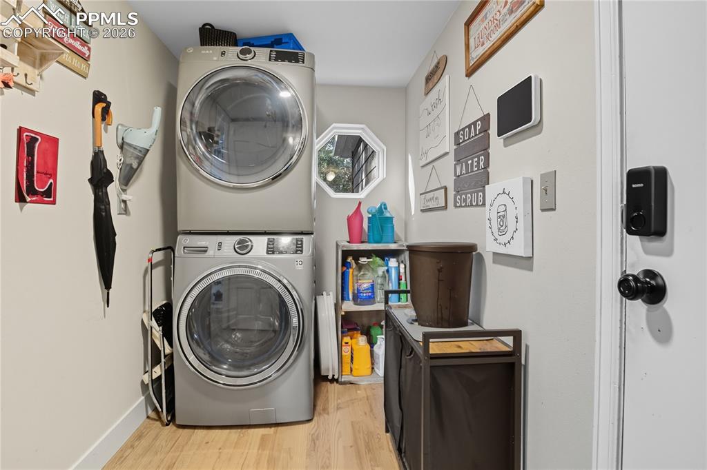 Image 22 of 45: Laundry room featuring light wood-style flooring and stacked washer and dry