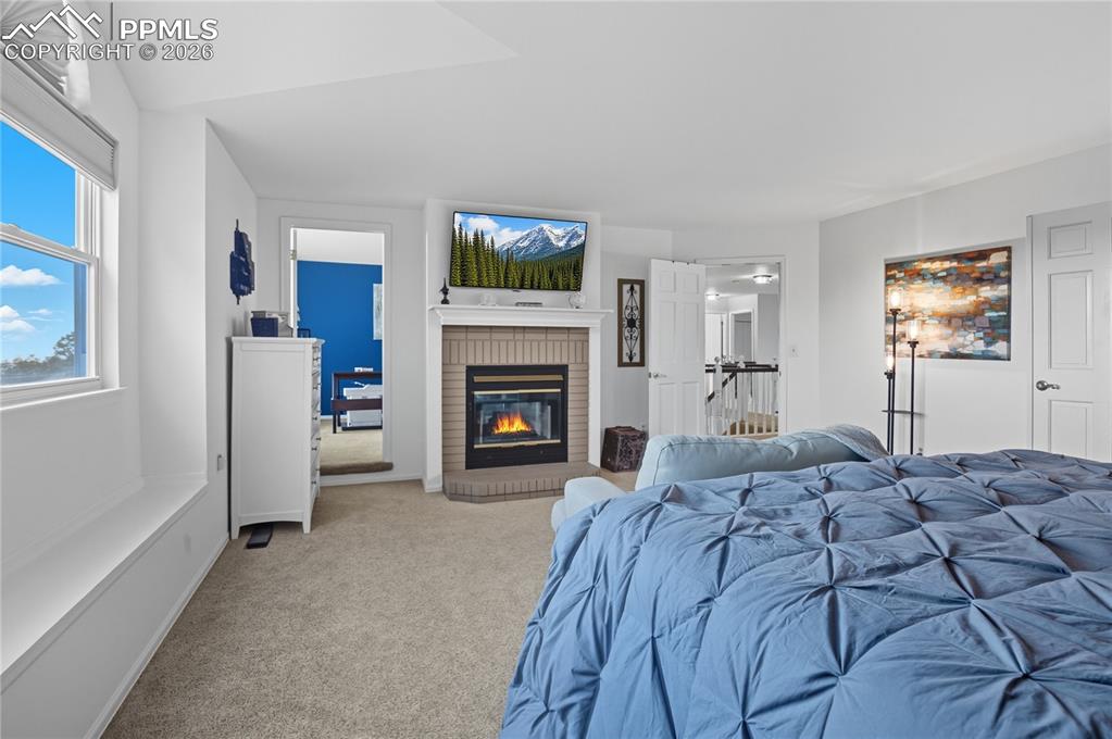 Image 26 of 45: Carpeted bedroom featuring a fireplace