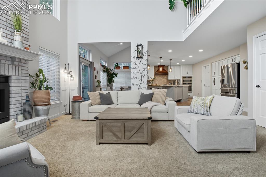 Image 3 of 45: Living area featuring recessed lighting, a brick fireplace, a high ceiling,