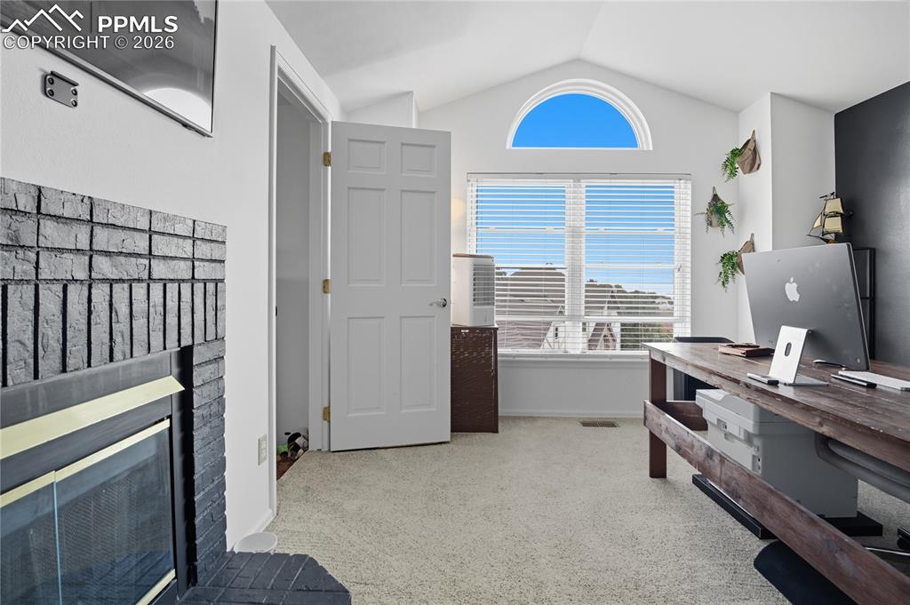 Image 31 of 45: Office with light colored carpet and a fireplace