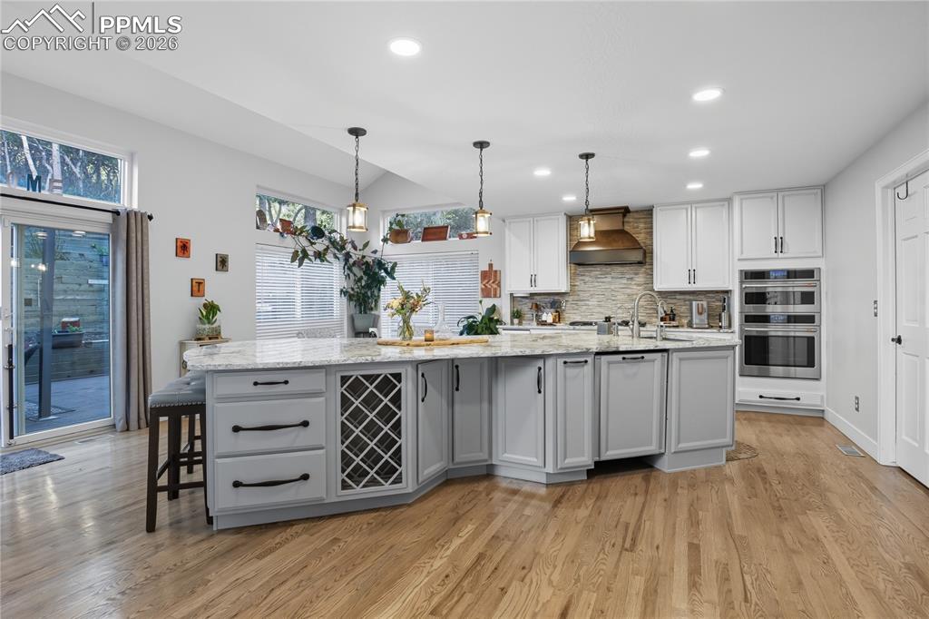 Image 4 of 45: Kitchen featuring decorative backsplash, light stone counters, decorative l