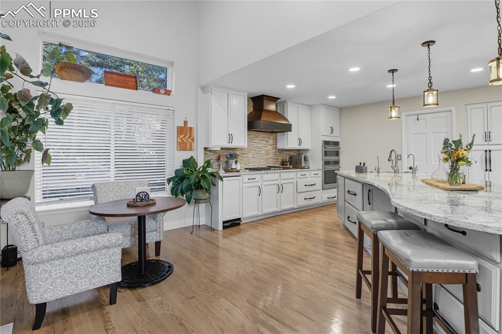 Image 5 of 45: Two tone kitchen with a breakfast bar area, light stone counters, pendant l