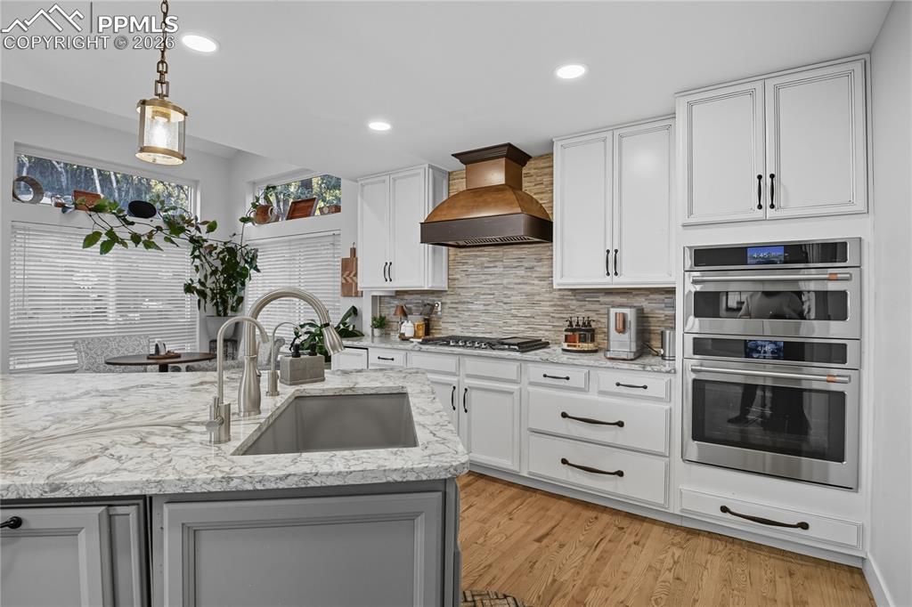 Image 6 of 45: Kitchen featuring stainless steel appliances, white cabinets, light stone c