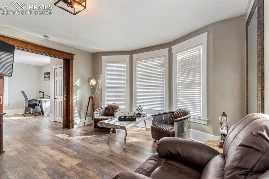 Image 10 of 43: Living room with an office area, baseboards, and wood finished floors