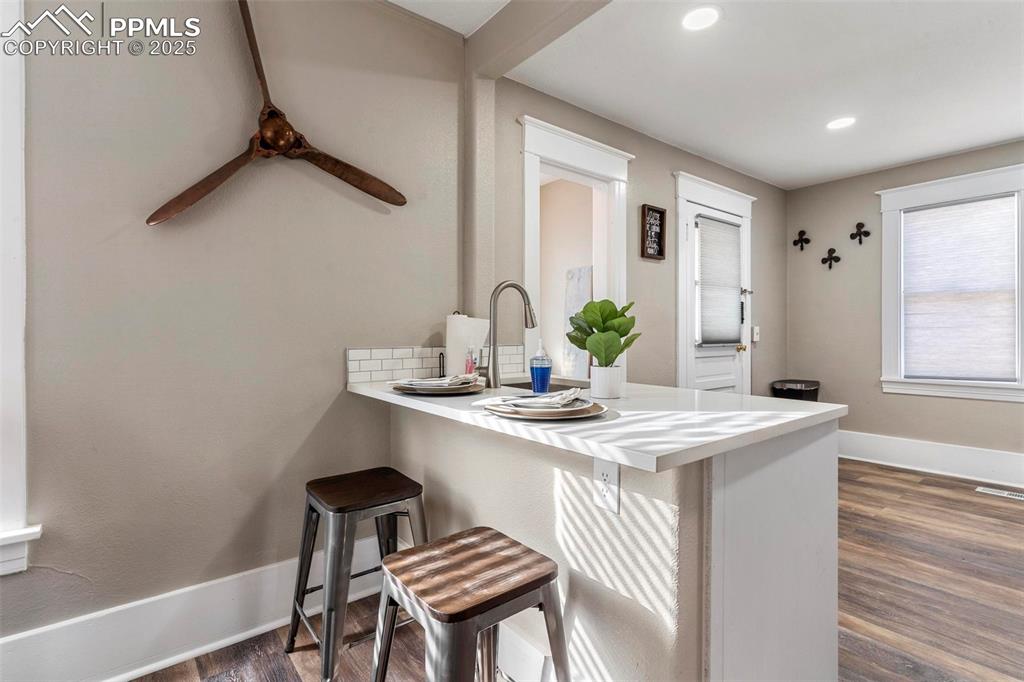 Image 11 of 43: Kitchen with dark wood-type flooring, a kitchen bar, baseboards, a peninsul
