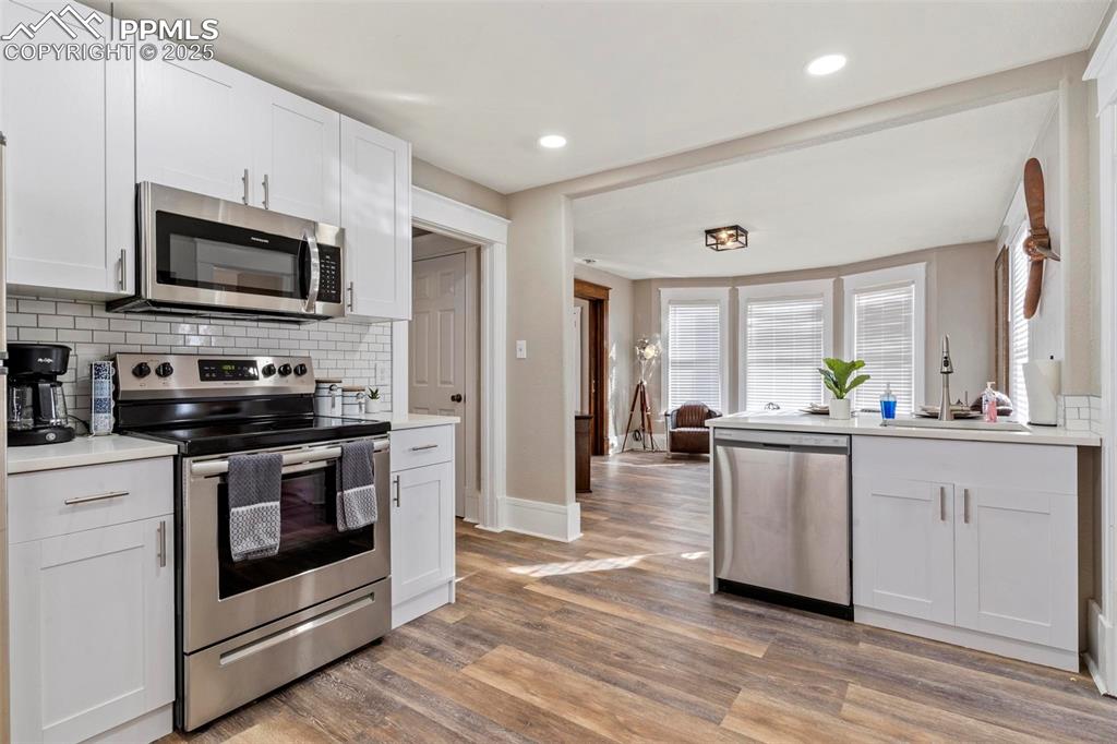 Image 14 of 43: Kitchen with stainless steel appliances, a sink, decorative backsplash, lig