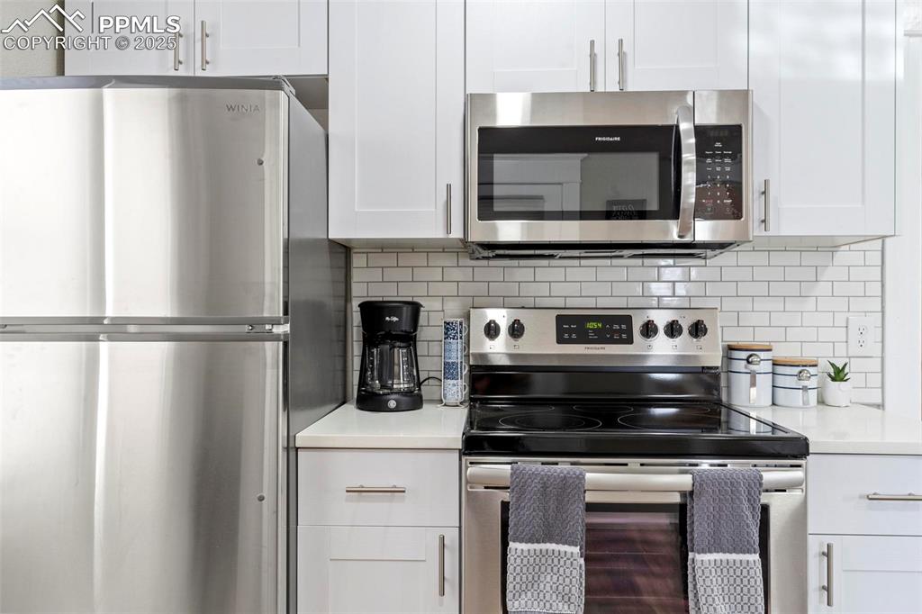 Image 16 of 43: Kitchen with stainless steel appliances, white cabinets, light countertops,