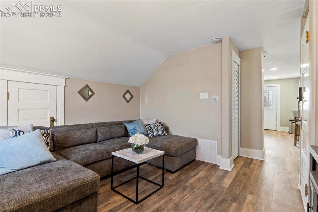 Image 19 of 43: Living room featuring wood finished floors, baseboards, and lofted ceiling
