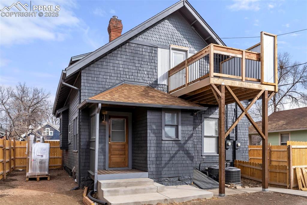 Image 2 of 43: Rear view of property featuring a chimney, a shingled roof, central air con