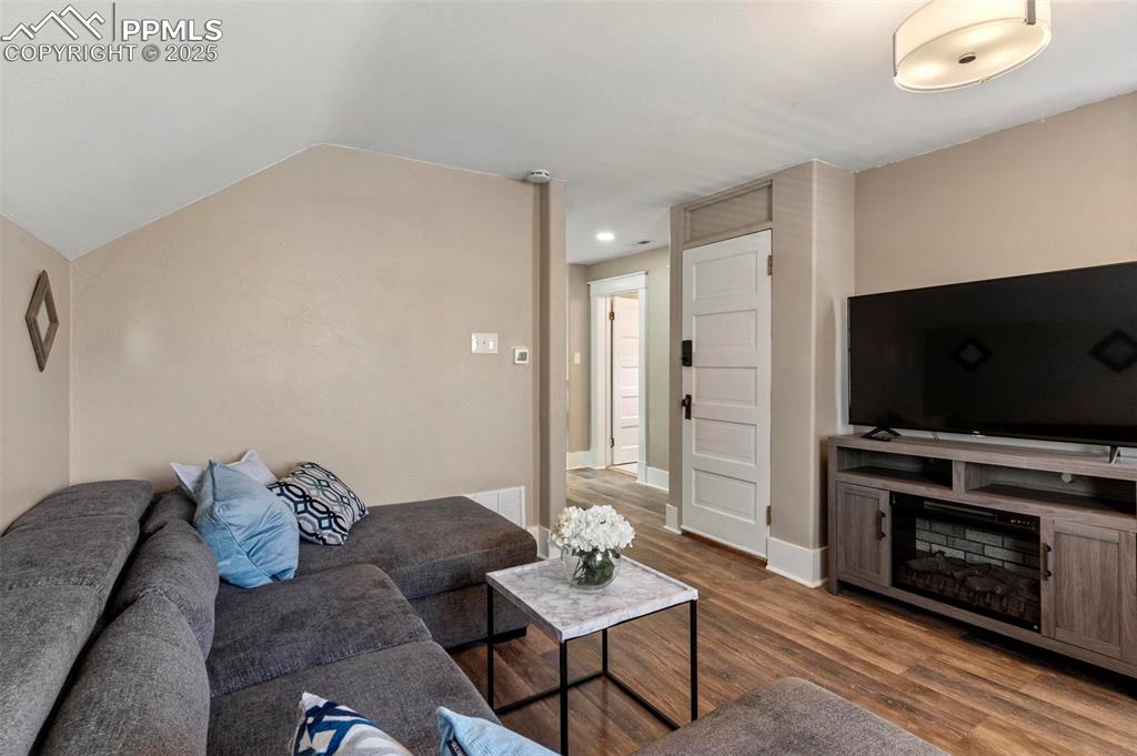 Image 20 of 43: Living room featuring wood finished floors, lofted ceiling, baseboards, and