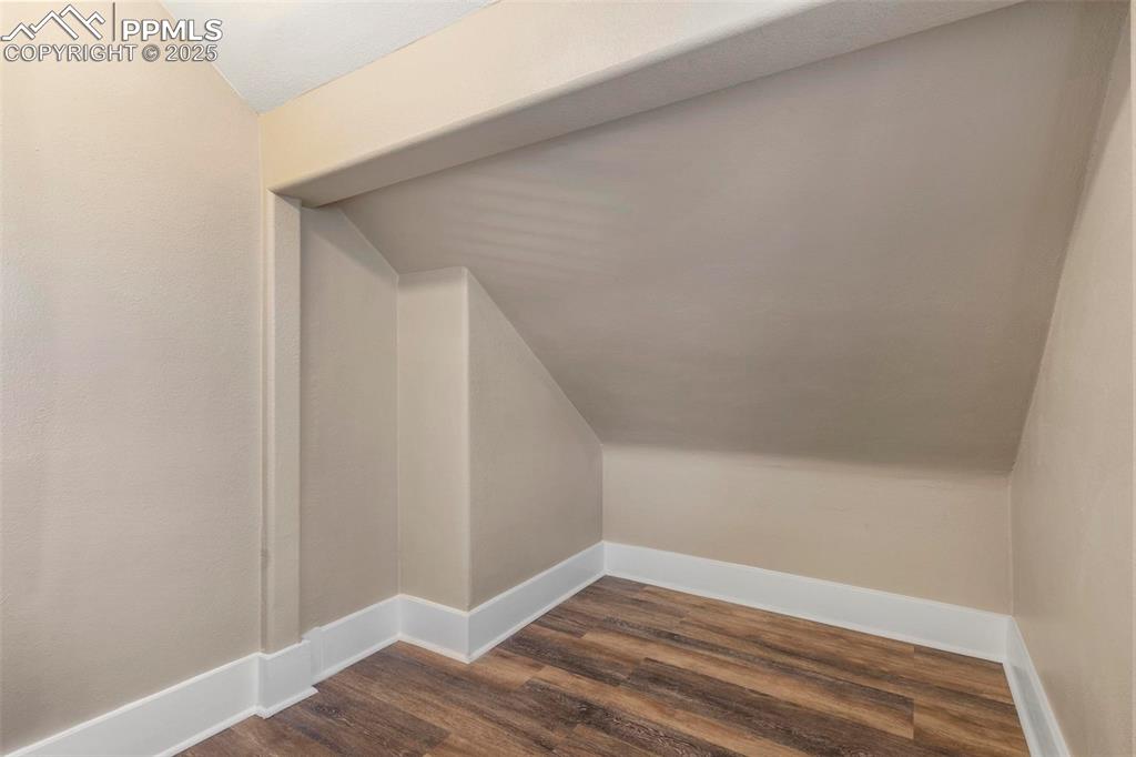 Image 21 of 43: Bonus room with lofted ceiling, dark wood finished floors, and baseboards