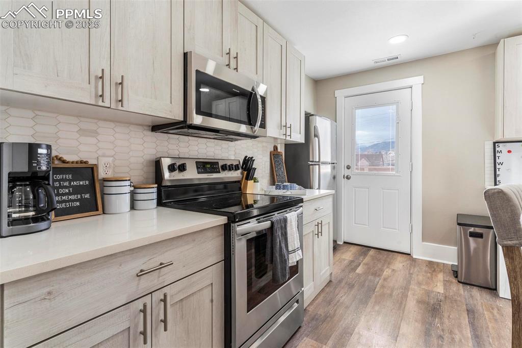 Image 25 of 43: Kitchen featuring appliances with stainless steel finishes, light wood-styl