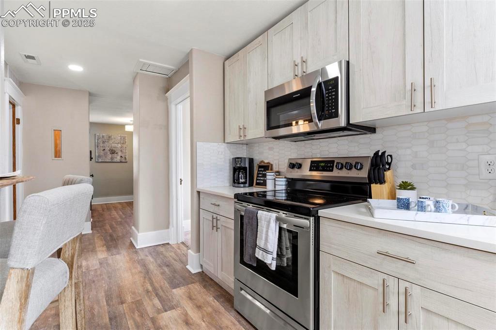 Image 26 of 43: Kitchen with appliances with stainless steel finishes, light countertops, b