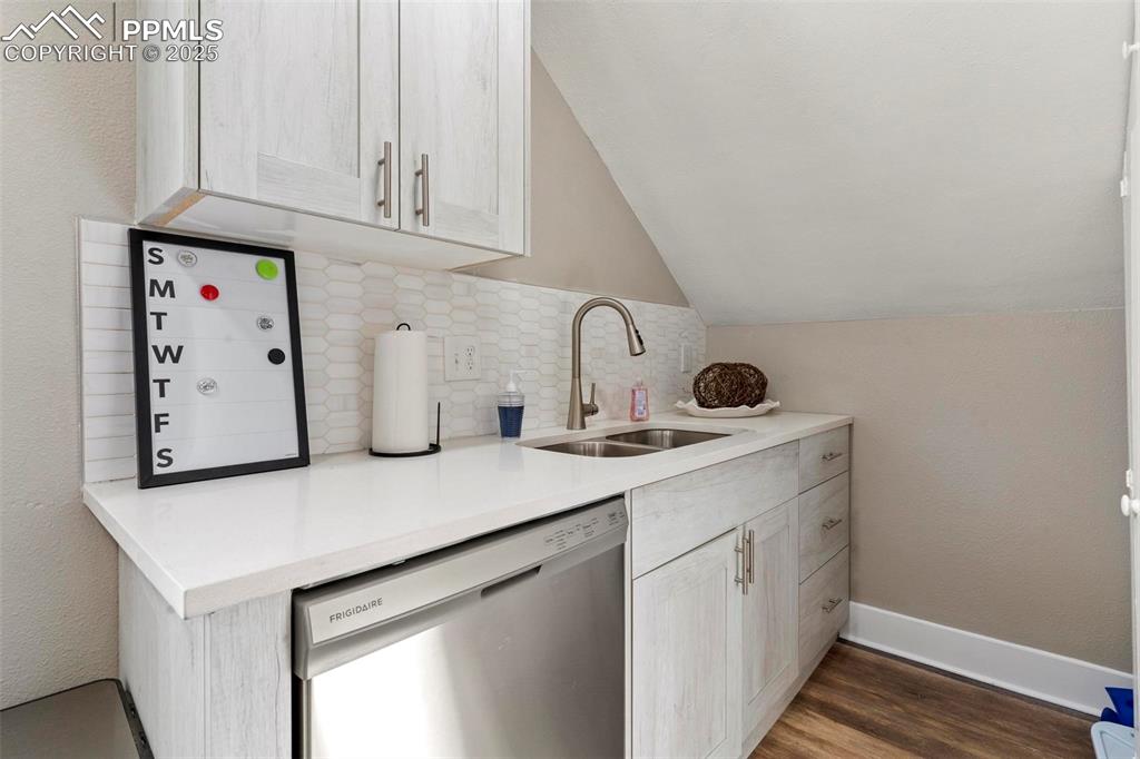 Image 27 of 43: Kitchen with stainless steel dishwasher, a sink, lofted ceiling, backsplash