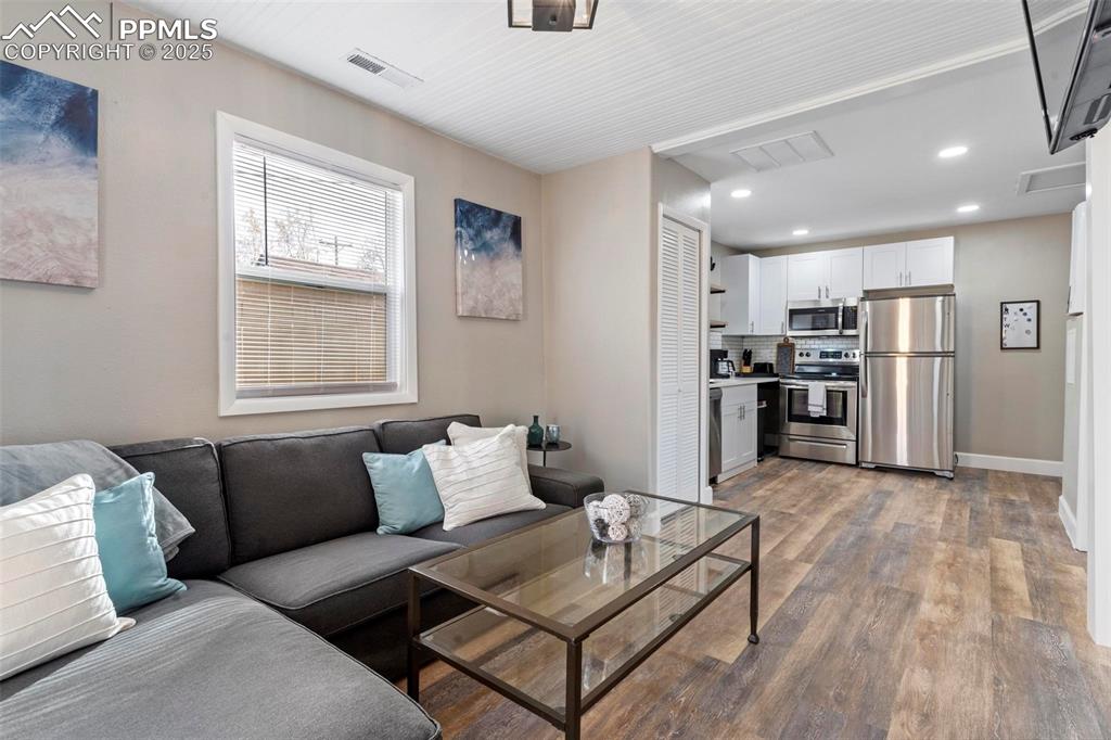 Image 31 of 43: Living room featuring light wood-style floors, recessed lighting, and baseb