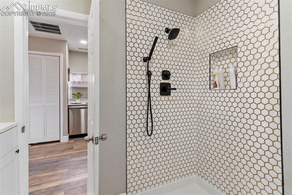 Image 35 of 43: Bathroom featuring tiled shower, wood finished floors, and vanity