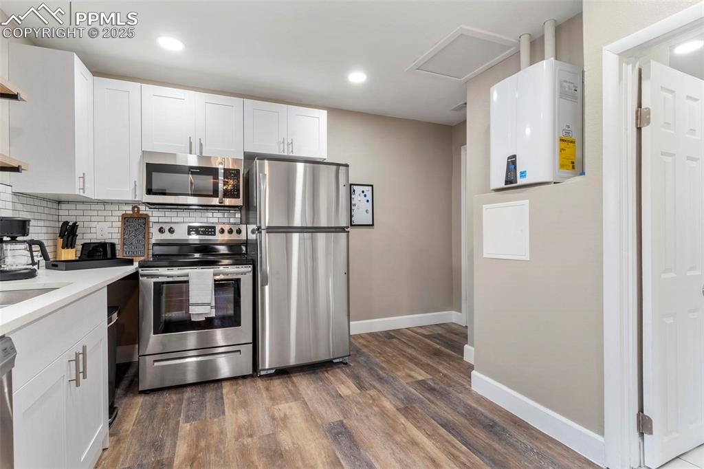 Image 36 of 43: Kitchen with stainless steel appliances, white cabinets, baseboards, dark w